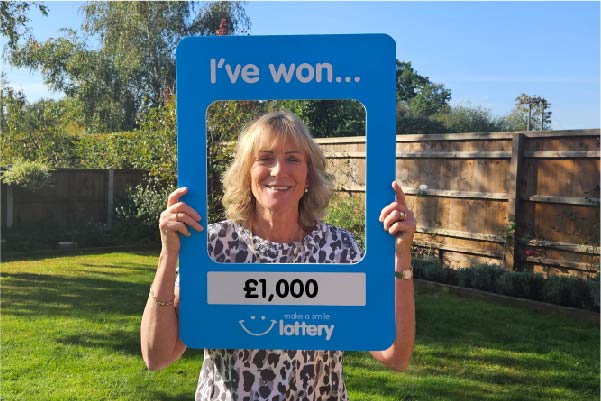 £1000 make a smile lottery winner holding a sign of her winning total