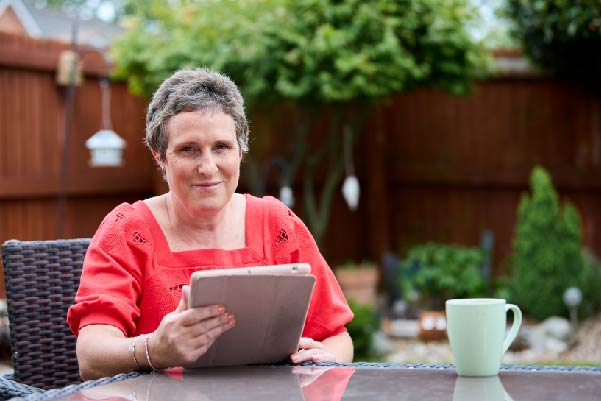 Emma in back garden holding an ipad