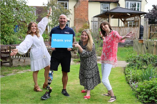 Group of young women throwing their hands in the air smiling, and a limbless veteran smiling holding a thank you sign.