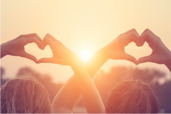 Two people holding their hands in a heart shape