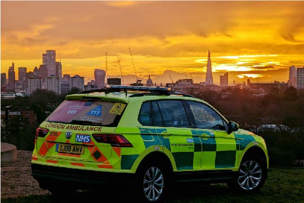 London ambulance car parked with city skyline at sunset