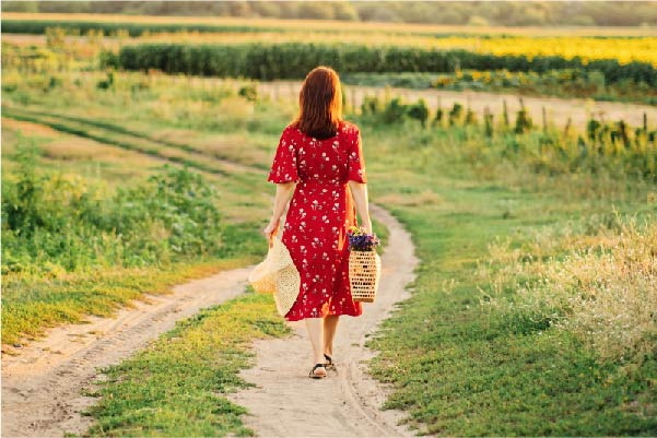 Lady walking through the fields with brown hair wearing a red dress