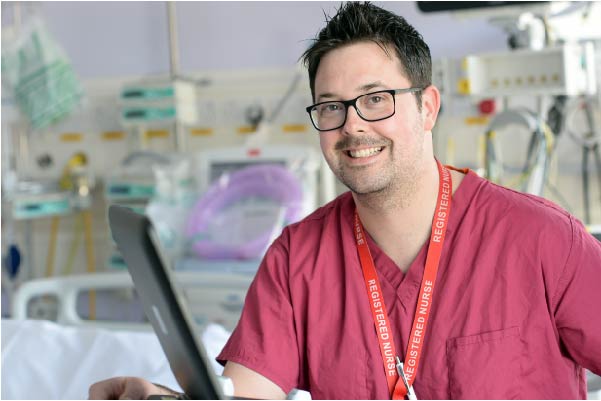 Male nurse smiling wearing red scrubs