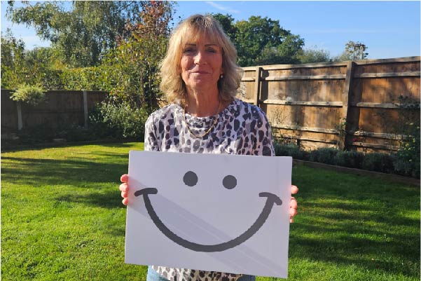 Stella holding a sign with smile logo from make a smile lottery